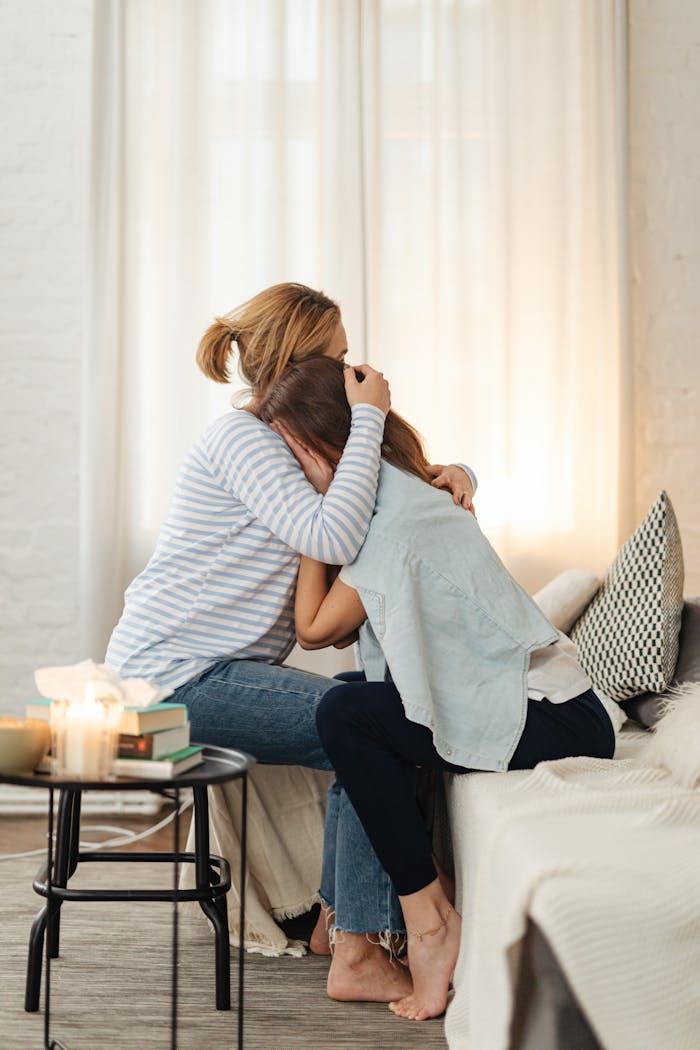 A comforting moment between mother and daughter in a cozy living room setting.